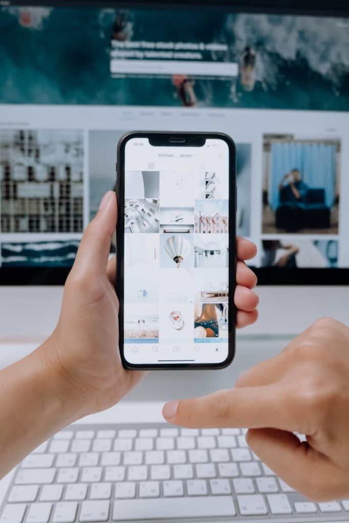 pexels photo 5082578 Person using smartphone to browse photos, office desktop setup.